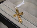 une croix en or suspendue à un cordon blanc, posée sur une boîte noire