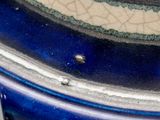 a close up of a blue and white vase with a bird on it