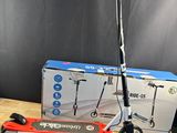 une trottinette électrique posée sur une table en bois, à côté d'une boîte