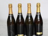 four bottles of champagne lined up on a marble counter top