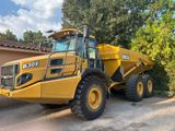 un camion-benne jaune garé devant une maison