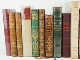 many old books lined up on a shelf next to each other