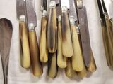 several knives and spoons are lined up on a table