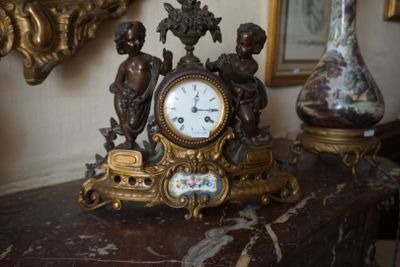 une horloge posée sur une table, à côté d'un vase