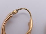 two pairs of gold hoop earrings on a white surface