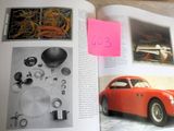 an open book with a picture of a red car and a pink post it note