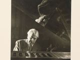 black and white photograph of a man sitting at a desk with a keyboard