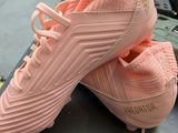 pink adidas soccer shoes on a table in a warehouse