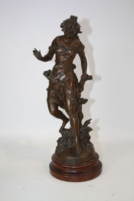 statue en bronze d'une femme tenant un oiseau sur une base en bois