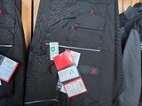 trois paires de pantalons noirs suspendus à un portant dans un magasin