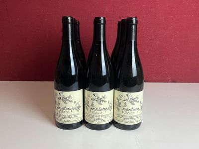 trois bouteilles de vin posées sur une table près d'un mur rouge