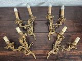 three antique brass wall sconces with white candles on a wooden table
