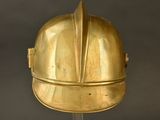 a gold helmet on a stand against a black background