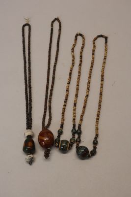 four necklaces with beads and a bead on a white surface