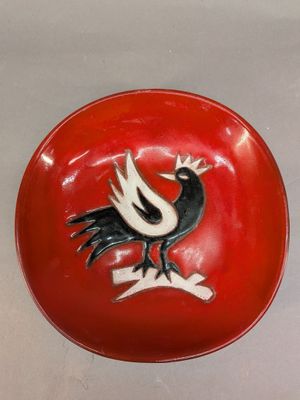 a red bowl with a black and white bird on it