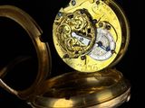 a close up of a gold pocket watch on a black surface