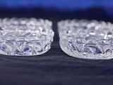 two clear glass bowls sitting on top of a black cloth