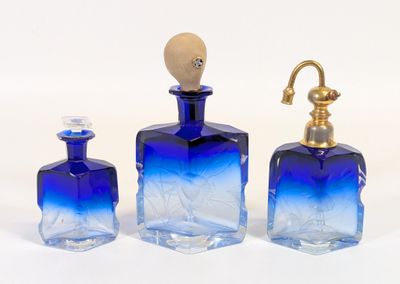 trois bouteilles en verre bleu et un robinet doré posés sur un plan de travail blanc