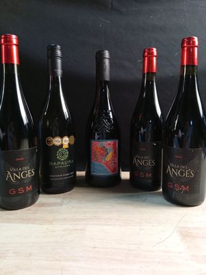 six bouteilles de vin rouge sont alignées sur une table