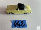 une petite voiture jaune posée à côté d'une feuille de papier bleue