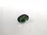 a green tourmaline stone on a white surface
