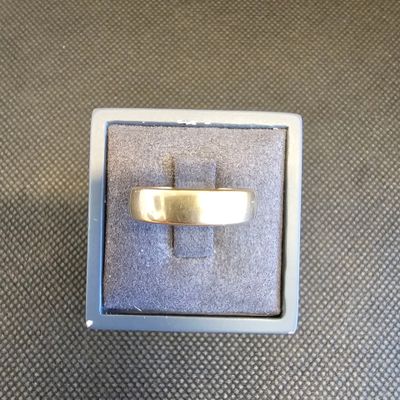 une photo représentant une bague en or dans un coffret en argent posé sur une table