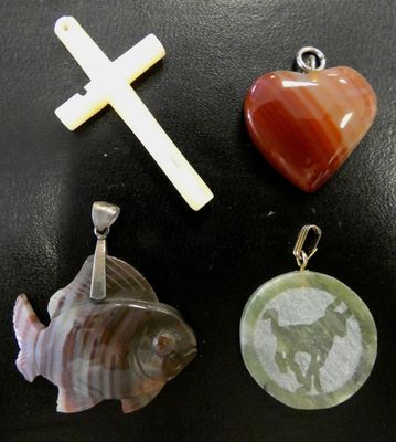trois types de pendentifs différents et une croix posés sur une table