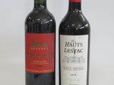 two bottles of red wine sitting next to each other on a table