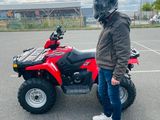 a man standing next to a red four wheeler atv