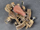 an old brass sexet with a wooden handle on a gray surface