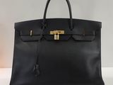 un sac à main en cuir noir muni d'un fermoir doré sur la poignée