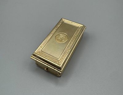 un étui à cigarettes plaqué or, orné d'un motif élaboré sur le devant