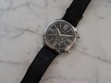 the watch is sitting on a marble surface with a black strap