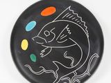 a black plate with a drawing of a fish on it
