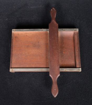 un petit couteau posé sur un plateau en bois, lui-même posé sur une surface noire