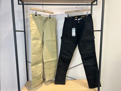 deux pantalons pour homme suspendus à un portant dans un magasin de vêtements