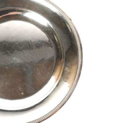 une assiette en argent posée sur une table, sur fond blanc