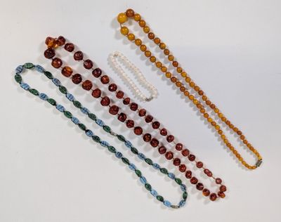quatre colliers de perles de différentes couleurs et tailles posés sur un fond blanc