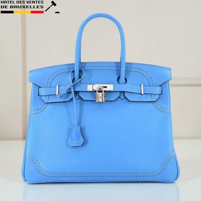 un sac à main en cuir bleu posé sur une table blanche