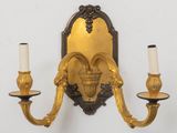 a gold wall sconce with two candles on it