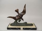 sculpture en bronze représentant un oiseau posé sur une vague, sur un socle en marbre