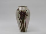a vase with a purple flower on it on a white surface