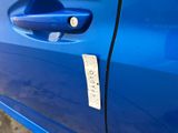 the door handle of a blue car with a sticker on it