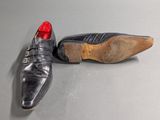 pair of black leather shoes with red soles sitting on a grey surface