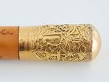 a close up of a wooden stick with a gold design on it