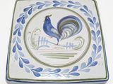 une assiette bleue et verte sur laquelle est représenté un coq