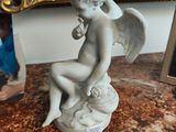 une statue représentant un ange assis sur une table en marbre
