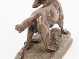 bronze statue of a dog on a rock on a white background