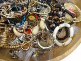 a wooden bowl filled with lots of assorted jewelry
