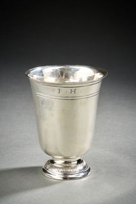 an antique silver cup on a pedestal on a gray surface